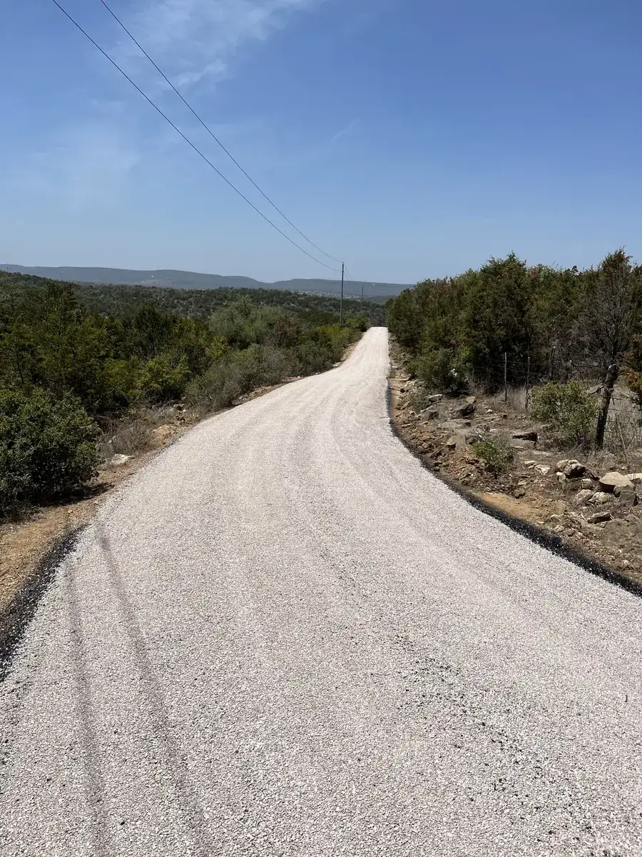 Fresh chip seal road curving through juniper-covered hills